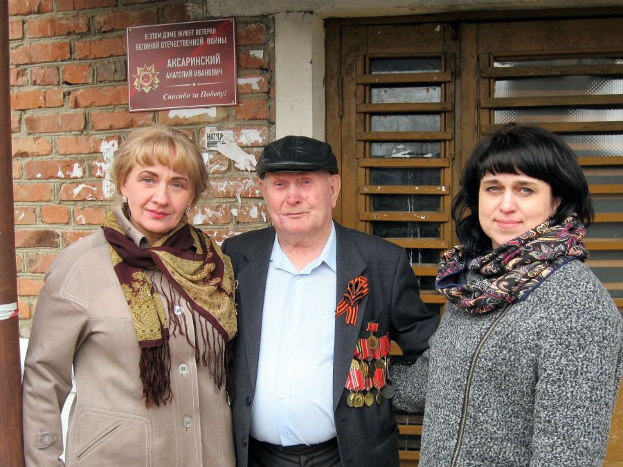 А. И. Аксаринский (в центре) у подъезда своего дома с персональной табличкой.